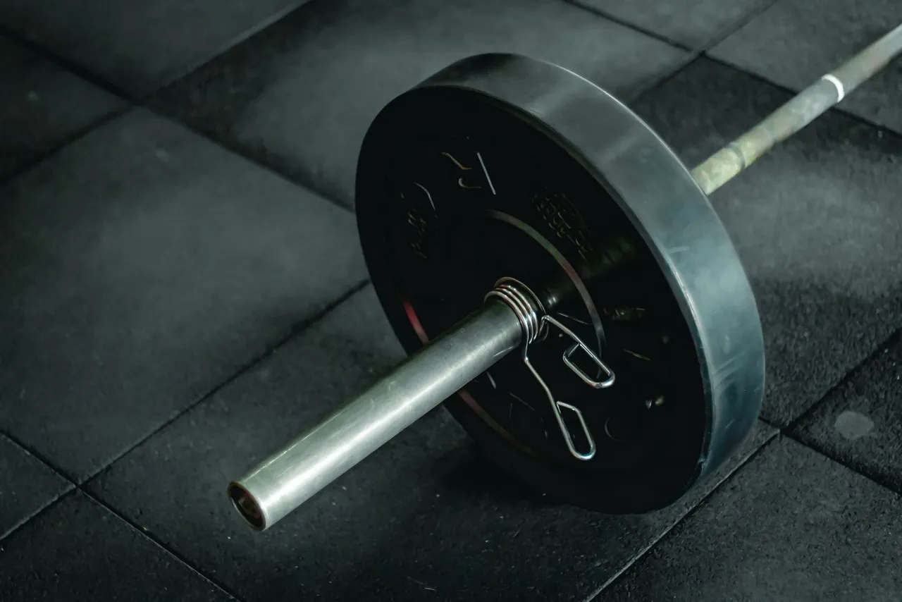 Barra con discos en un gimnasio oscuro